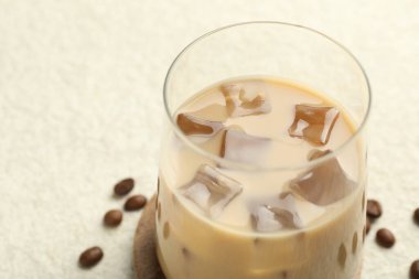 Coffee cream liqueur in glass and beans on white textured table, closeup. Space for text
