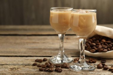 Bardakta kremalı kahve likörü ve ahşap masada fasulye, yakın plan. Metin için boşluk