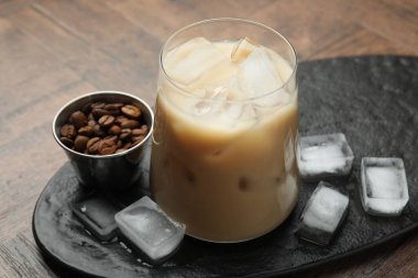 Bardakta kremalı kahve likörü, ahşap masada dondurma ve fasulye, yakın plan.