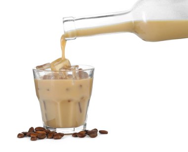 Pouring coffee cream liqueur from bottle into glass isolated on white