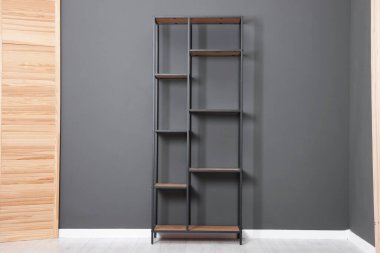 Boş raf ünitesi ve kapalı alanda gri duvarın yanında katlanan ekran