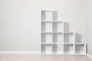 Empty shelving unit near light grey wall indoors, space for text