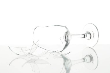 Pieces of broken wine glass on table against white background, closeup