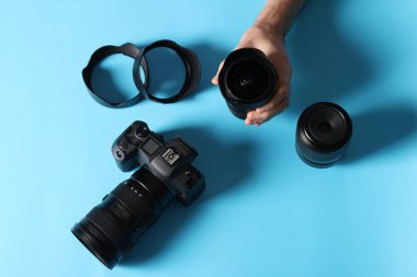 Açık mavi arka planda profesyonel kamera ve ekipmana sahip fotoğrafçı, üst görünüm