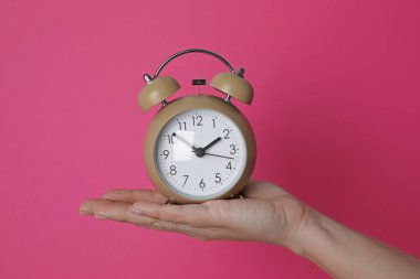 Kırmızı arka planda çalar saati olan kadın, yakın plan.