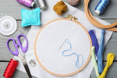 Gri ahşap masaya nakış işlemek için farklı dikiş malzemeleri.