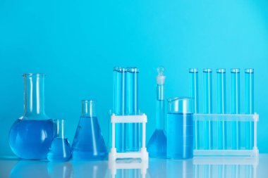 Aynanın yüzeyinde mavi arkaplana karşı sıvı bulunan laboratuvar camları.