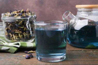 Delicious butterfly pea flower tea on wooden table against brown background