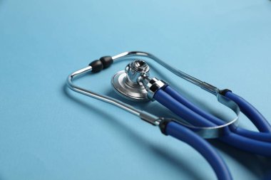 Açık mavi arka planda steteskop, yakın plan. Tıbbi araç