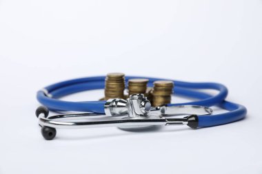 Işık arkaplanındaki stetoskop ve madeni paralar, yakın plan