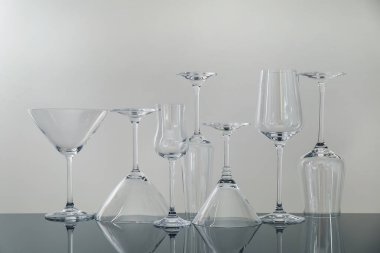 Gri arkaplana karşı ayna yüzeyinde birçok boş bardak