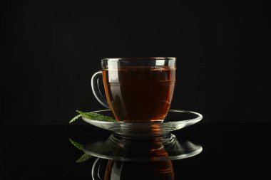 Cam bardakta Aromatik çay ve koyu ayna masasında nane.