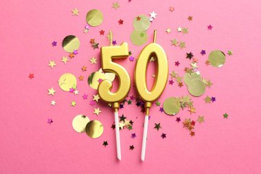 50. yaş günü. Pembe arkaplandaki mumlar ve konfetiler düzdü.