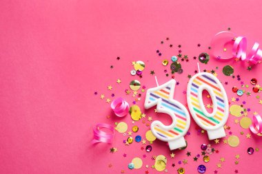 30th birthday. Number shaped candles and confetti on pink background, flat lay. Space for text