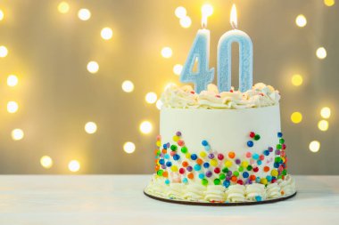 40. yaş günü. Beyaz ahşap masada yanan mumlara sahip pasta. Arka planda bulanık ışıklar, yakın çekim ve metin için boşluk. Bokeh etkisi