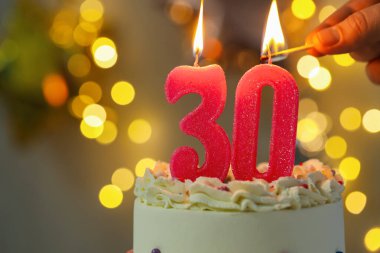 30. yaş günü. Kek üzerindeki mumların yanma sayısı bulanık arka planda ışıklar, yakın plan ve metin için boşluk. Bokeh etkisi
