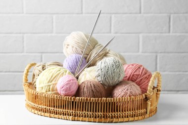 Hasır sepetin içinde renkli iplik topları beyaz masada, yakın plan