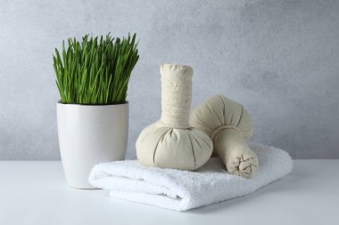 Beyaz masa üzerinde buğday çimi ve bitkisel poşetlerle spa kompozisyonu