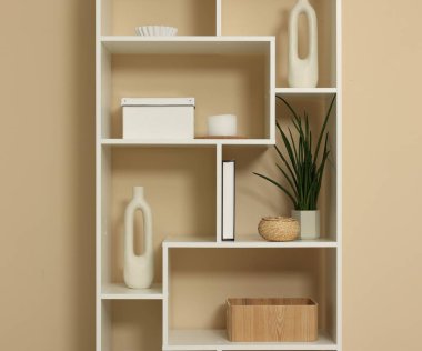 Shelving unit with decor near beige wall indoors