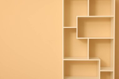 Empty shelving unit near beige wall indoors, closeup. Space for text