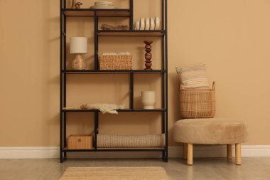 Dekor, sepet ve yastıklı raf ünitesi bej duvarın yanında.