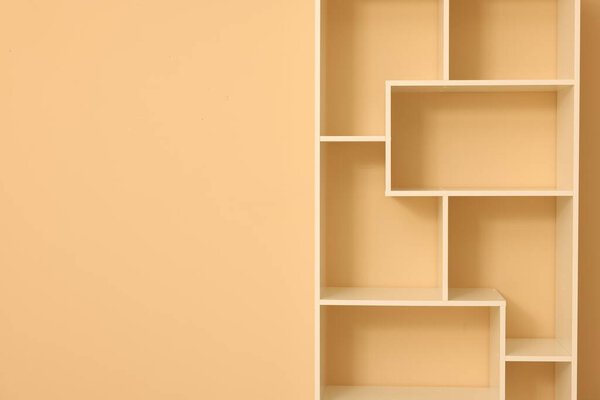 Empty shelving unit near beige wall indoors, closeup. Space for text