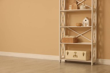 Shelving unit with decor near beige wall indoors, space for text