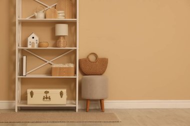 Dekor, dışkı ve hasır çantalı raf ünitesi, kapalı alanda bej duvar, metin için boşluk