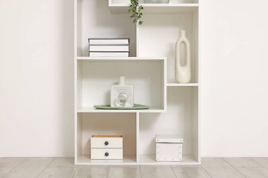 Beyaz duvarın yanında dekorlu raf ünitesi.