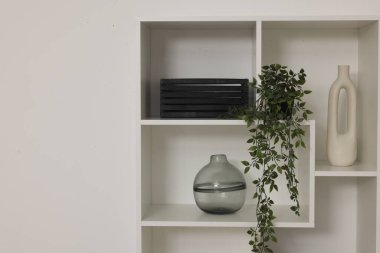 Beyaz duvarın yanında dekorlu raf ünitesi, metin için boşluk