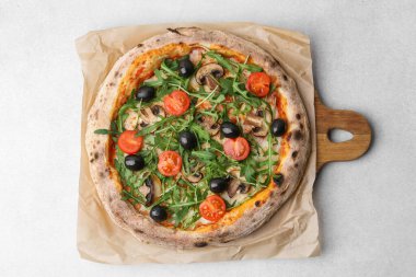 Kiraz domatesli lezzetli pizza, siyah zeytin, mantar ve roka açık gri masada, üst manzara