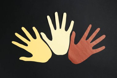 Irkçılığı bırak. Siyah arkaplanda farklı renkte el kâğıdı figürleri, üst görünüm