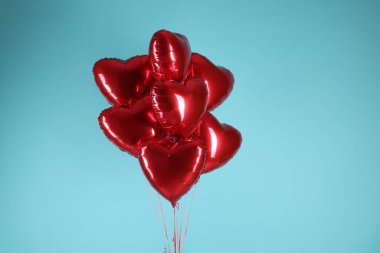 Açık mavi arka planda bir sürü kırmızı kalp şeklinde balon. Sevgililer Günün kutlu olsun.