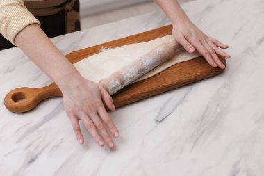 Hafif mermer masada hamuru yuvarlayan kadın, yakın plan. Kruvasan yapıyorum.