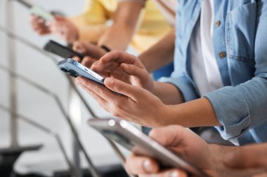 İnternet bağımlılığı. Merdivenlerde akıllı telefonları olan bir grup insan, yakın plan.