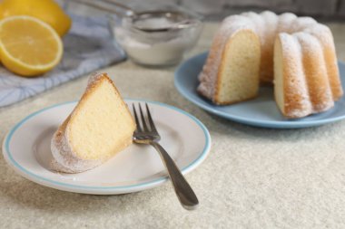 Bir parça leziz limonlu kek, pudra şekeri ve çatalla ince desenli masa, yakın plan.