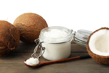 Hindistan cevizleri, pişirme yağı ve kaşık ahşap masada beyaz arka planda