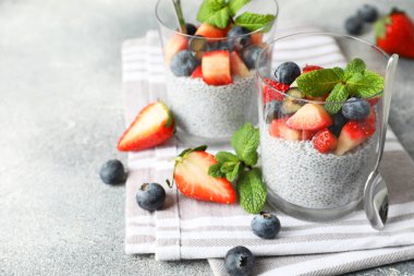 Çilekli chia pudingi, yaban mersini ve nane şekeri. Gri masada, yakın plan. Metin için boşluk
