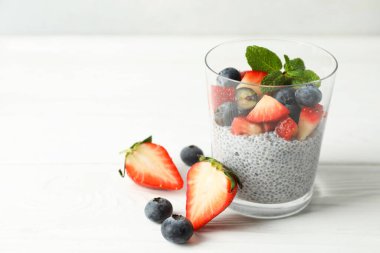 Çilekli chia pudingi, yaban mersini ve nane şekerli beyaz ahşap masa, yakın plan. Metin için boşluk