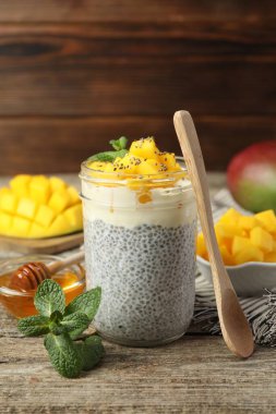 Bardakta mangolu lezzetli chia pudingi, ahşap masada nane ve bal.
