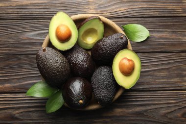 Avokado ve yaprakları ahşap masada, düz bir şekilde yatıyordu.