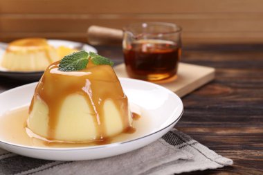 Karamel soslu lezzetli puding ve ahşap masada nane şekeri, yakın plan.