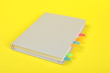 Sarı arkaplan üzerine renkli sekmeler içeren kitap, yakın plan