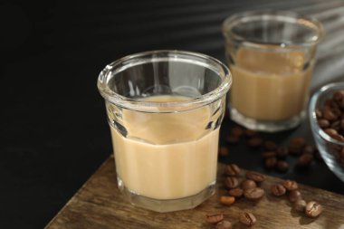 Bardakta kremalı kahve likörü ve siyah masada fasulye, yakın plan.