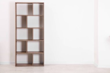 Empty wooden shelving unit near white wall indoors, space for text
