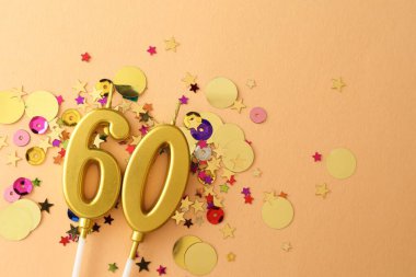 60. yaş günü. Bej arka planda mumlar ve konfeti var. Metin için boşluk