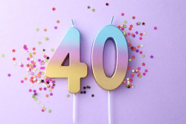 40th birthday. Number shaped candles and confetti on violet background, flat lay