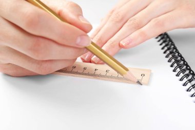 Masada cetvel ve kalemle çizim yapan kadın, yakın plan.