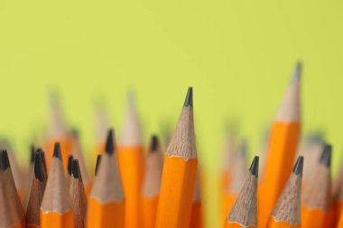 Yeşil arkaplanda birçok grafit kalem, yakın plan