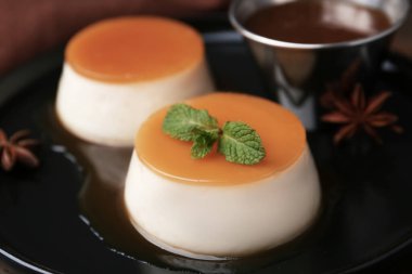 Tasty puddings with caramel sauce served on table, closeup